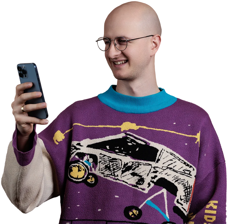 Rez smiling at his phone, wearing glasses and a purple sweater