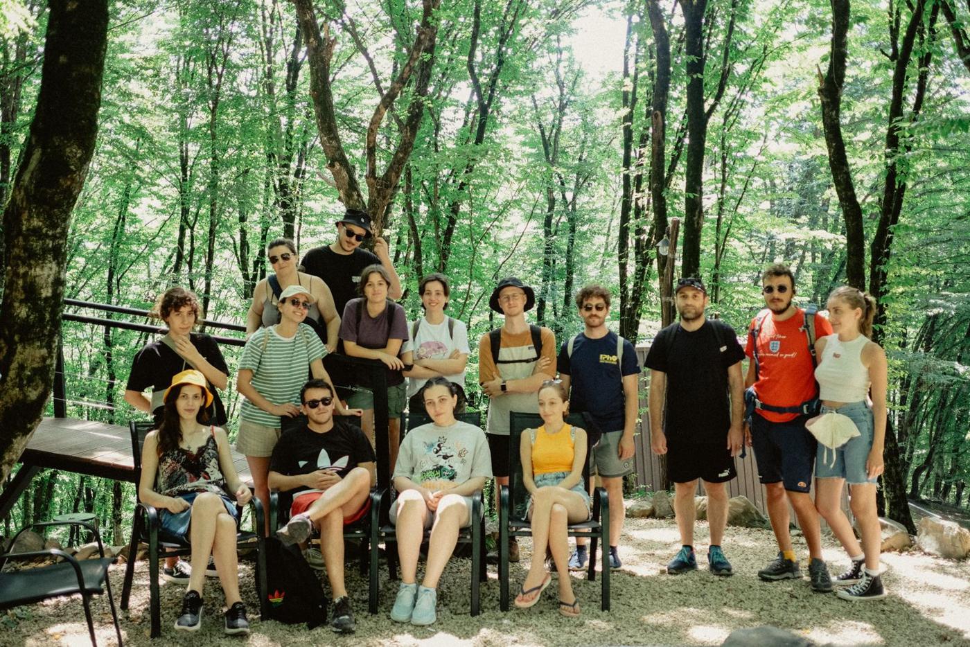 The eConsul team, about twenty people, posing together in a sunlit forest